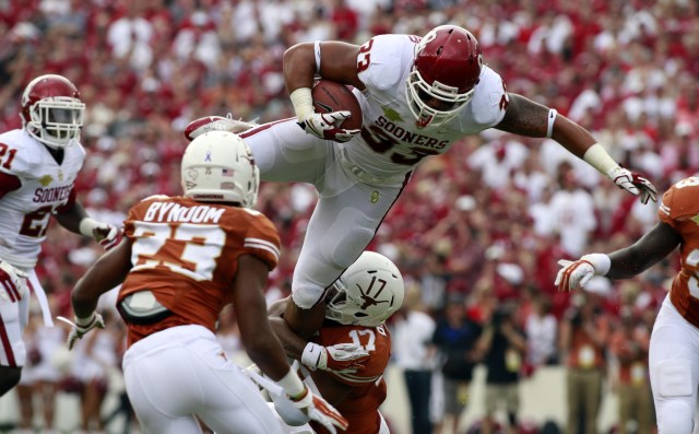 Oklahoma Sooners fullback Trey Millard jumps over Texas Longhorns safety Adrian Phillips during the Red River Rivalry at Cotton Bowl Stadium. (Tim Heitman - USA TODAY Sports)
