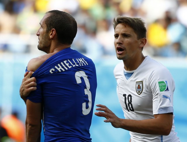 Italy's Giorgio Chiellini shows his shoulder, claiming he was bitten by Uruguay's Luis Suarez, as Uruguay's Gaston Ramirez approaches. (Tony Gentile, REUTERS)