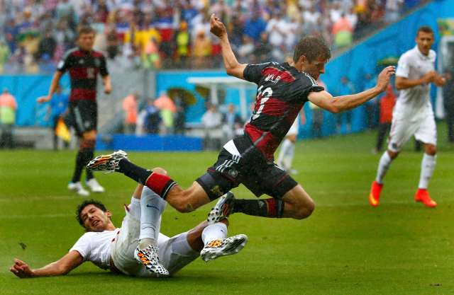 Omar Gonzalez of the U.S. (in white) tackles Germany's Thomas Mueller. (REUTERS/Tony Gentile)