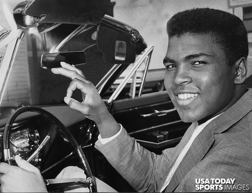 Muhammad Ali, then Cassius Clay, gives a victory sign from behind the wheel of his convertible after winning his driver's license back in 1963.  //  Credit: Bud Kamenish, The Courier-Journal, USA TODAY Sports