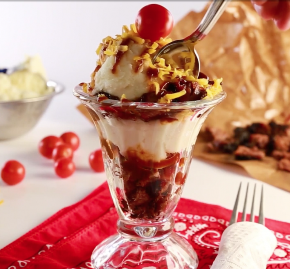 Photographic depiction of an ice cream sundae, based on one served during NASCAR races at the Kansas International Speedway. Visual shows an ice cream sundae glass layered with mashed potatoes instead of ice cream, brisket and barbecue sauce.