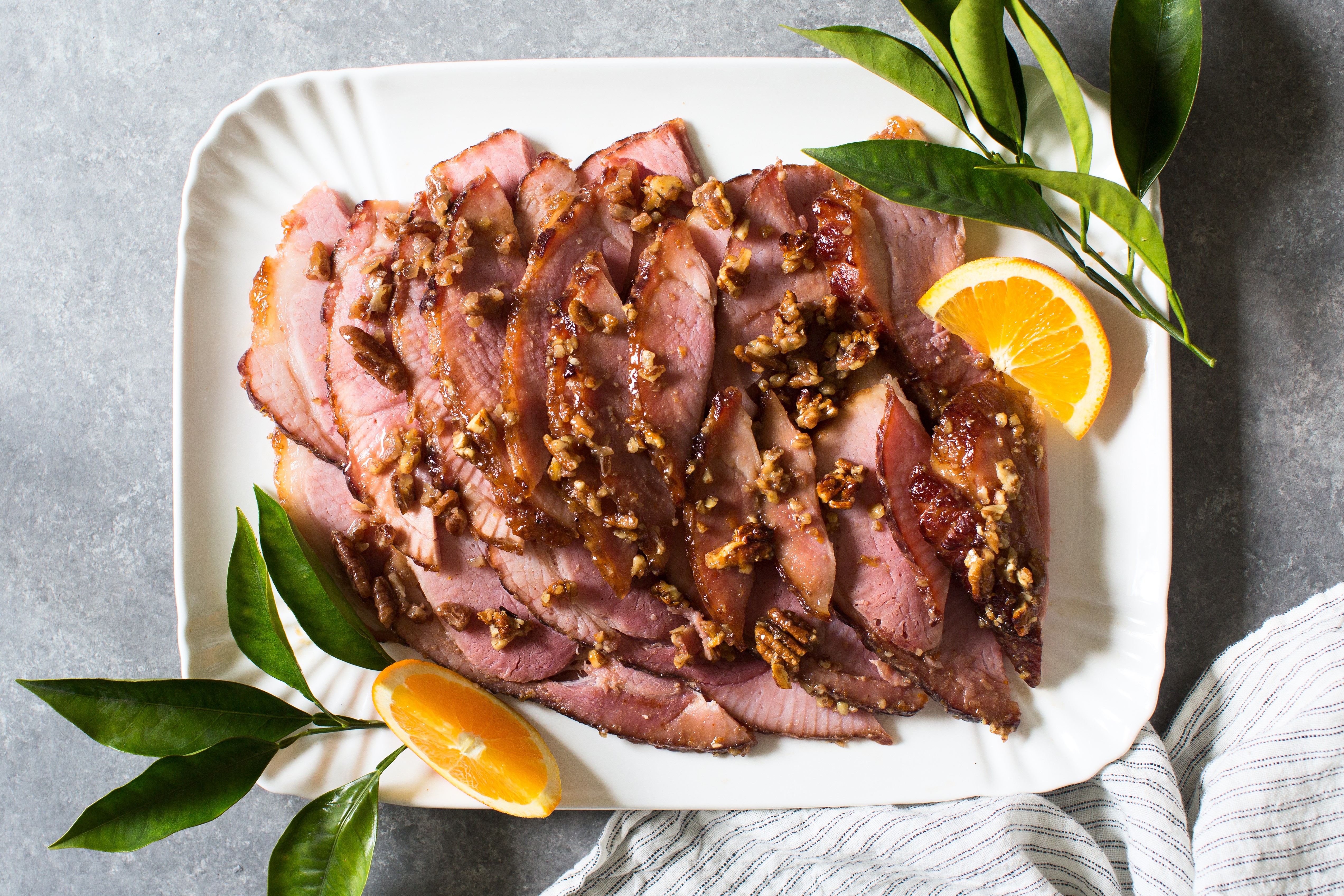 Coated with crunchy and naturally sweet fresh pecans, orange juice, bourbon and maple syrup, this recipe for Pecan, Orange and Bourbon Glazed ham hits the spot for savory and sweet lovers alike.
