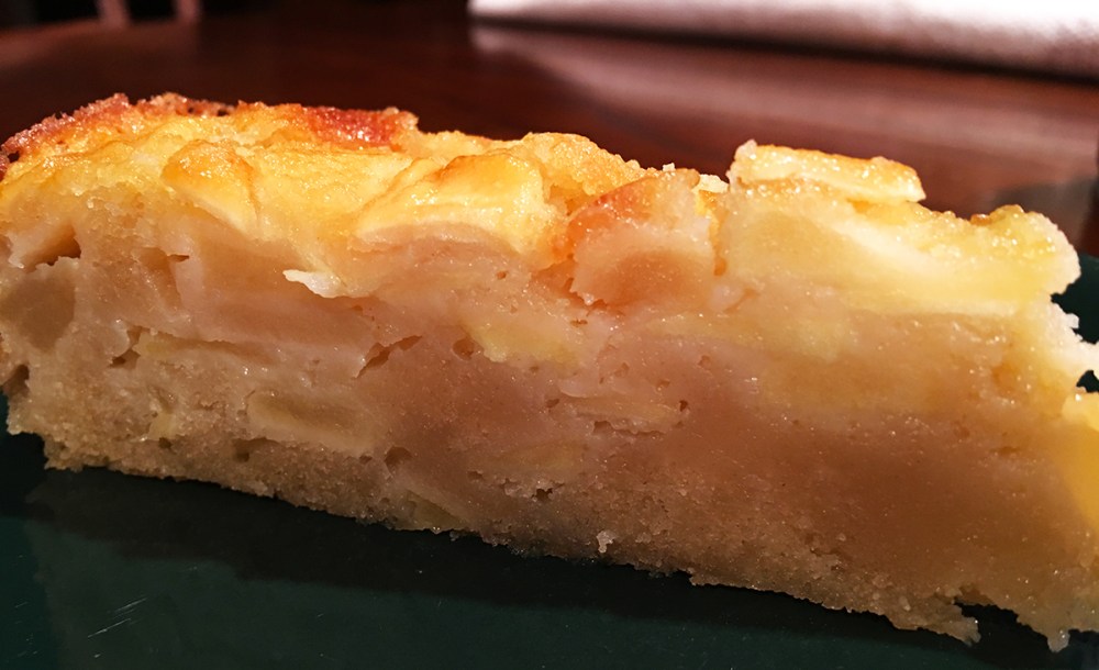 A slice of custard apple cake with a golden brown crust and fresh-baked apple filling. 
