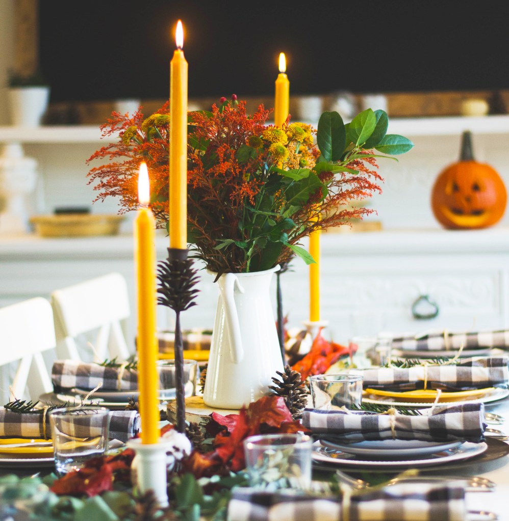 A beautiful Thanksgiving table set with candles and place settings ready for family and friends to enjoy breaking bread together. 