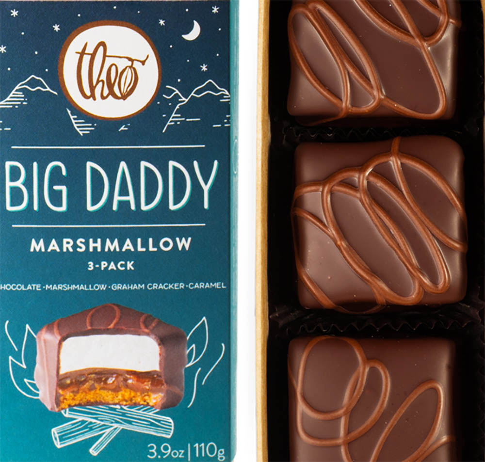 A Big Daddy marshmallow treat which is handmade graham cracker crust, a layer of buttery vanilla infused caramel and a fluffy marshmallow cloud on top, then enrobed in dark chocolate, and decorated with an alderwood smoked milk chocolate flourish.