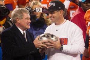 Clemson head coach Dabo Swinney (R) accepts the championship trophy from ACC commisioner John Swofford (L) after defeating the North Carolina Tar Heels in the ACC football championship game at Bank of America Stadium.
