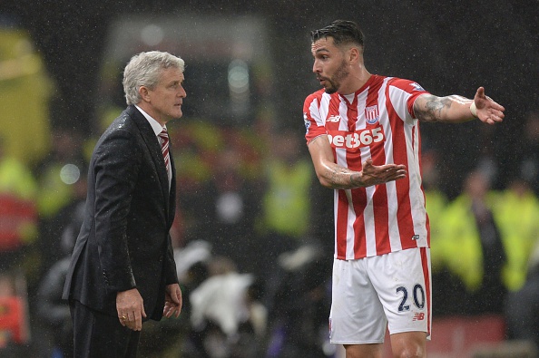 Stoke City's US defender Geoff Cameron (R) gestures as he talks with Stoke City's Welsh manager Mark Hughes (L) on the touchline during the English League Cup semi-final first leg football match at Britannia Stadium in Stoke-on-Trent, central England, on January 5, 2016. AFP PHOTO / OLI SCARFF RESTRICTED TO EDITORIAL USE. No use with unauthorized audio, video, data, fixture lists, club/league logos or 'live' services. Online in-match use limited to 75 images, no video emulation. No use in betting, games or single club/league/player publications. / AFP / OLI SCARFF (Photo credit should read OLI SCARFF/AFP/Getty Images)