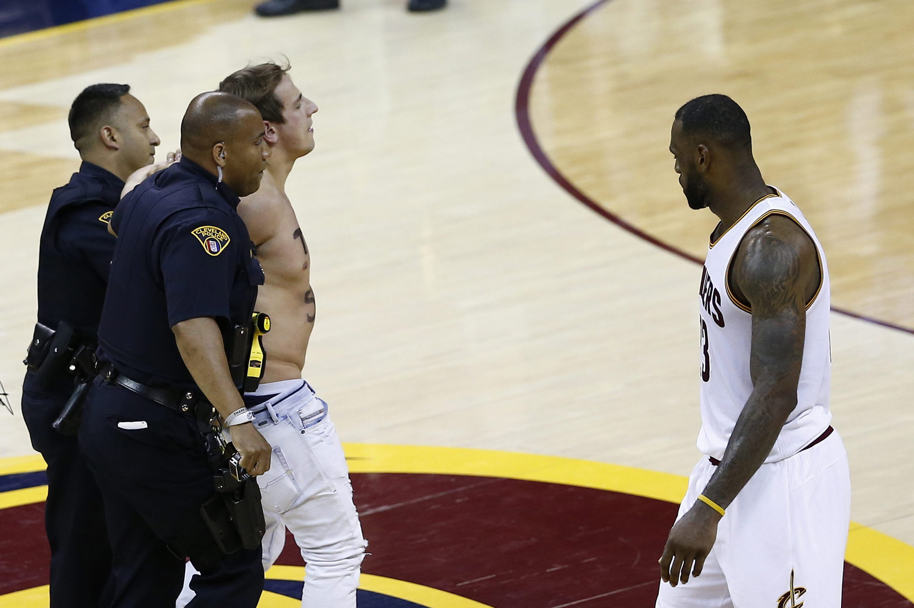 epa05356397 Cleveland Cavaliers player LeBron James (R) watches as the police walk a man in handcuffs off the court after he ran on to the court, stopping play during the second half of the NBA Finals basketball game four between the Golden State Warriors and the Cleveland Cavaliers at the Quicken Loans Arena in Cleveland, Ohio, USA, 10 June 2016. EPA/LARRY W. SMITH CORBIS OUT ORG XMIT: LWS113