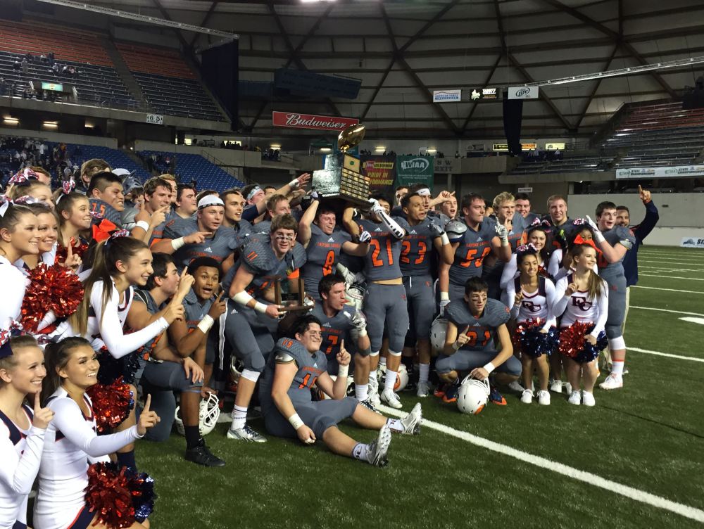 Eastside Catholic holds up its 3A state football trophy at the Tacoma Dome after knocking off Bellevue. 