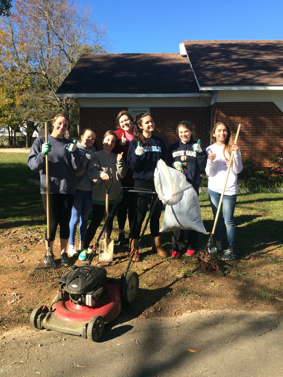 Members of SNHS posing with their yard work equipment outside the M.O.P. monastery.