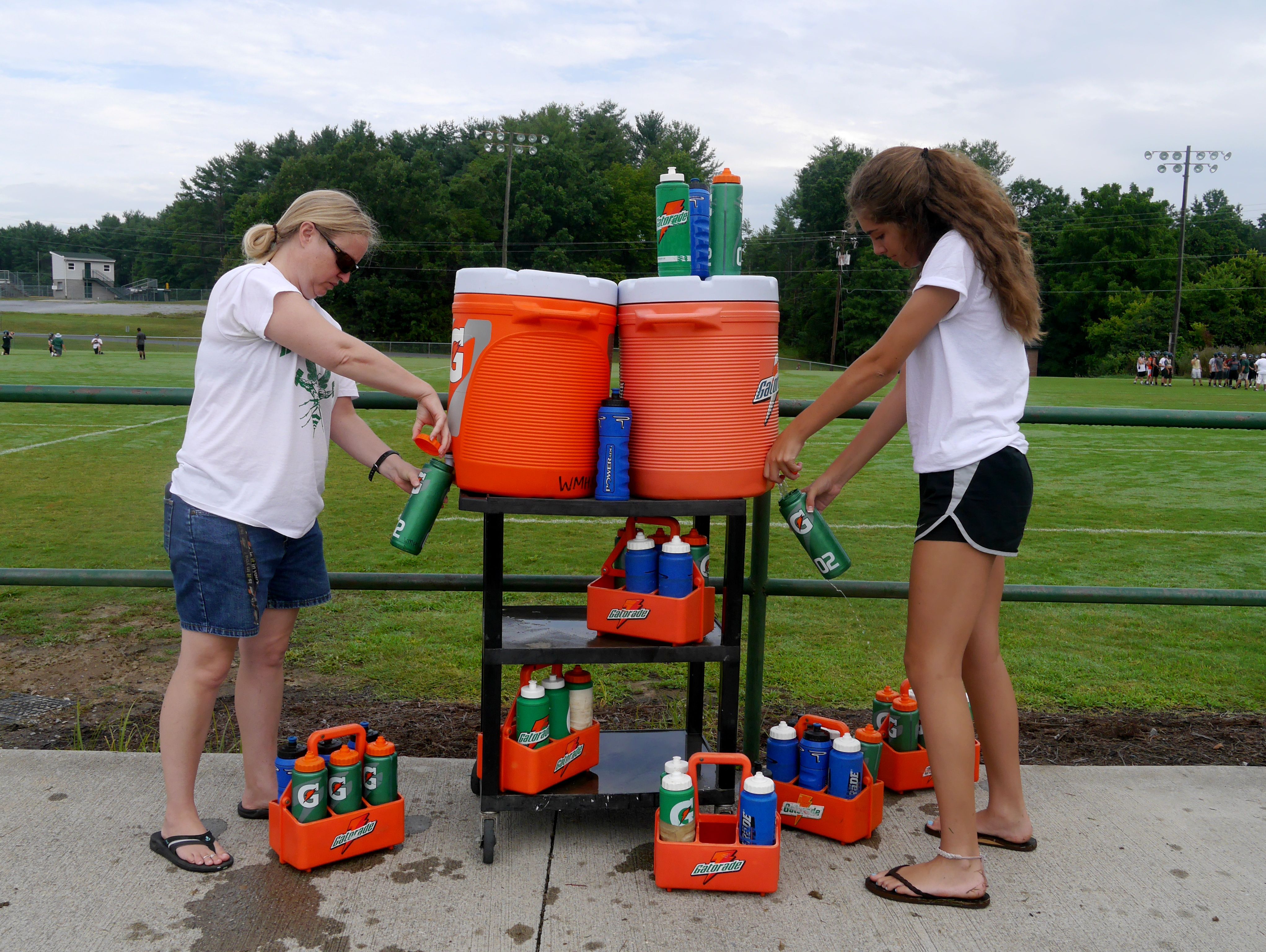 Wilson Memorial High School's athletic trainer Susanna Larner and senior Kylie Ritts refill bottles with water during the first day of football practice on Thursday, July 28, 2016.