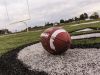 A football lays on the field in view of the end zone at a high school.