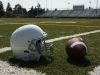 Football and football helmet on football field.