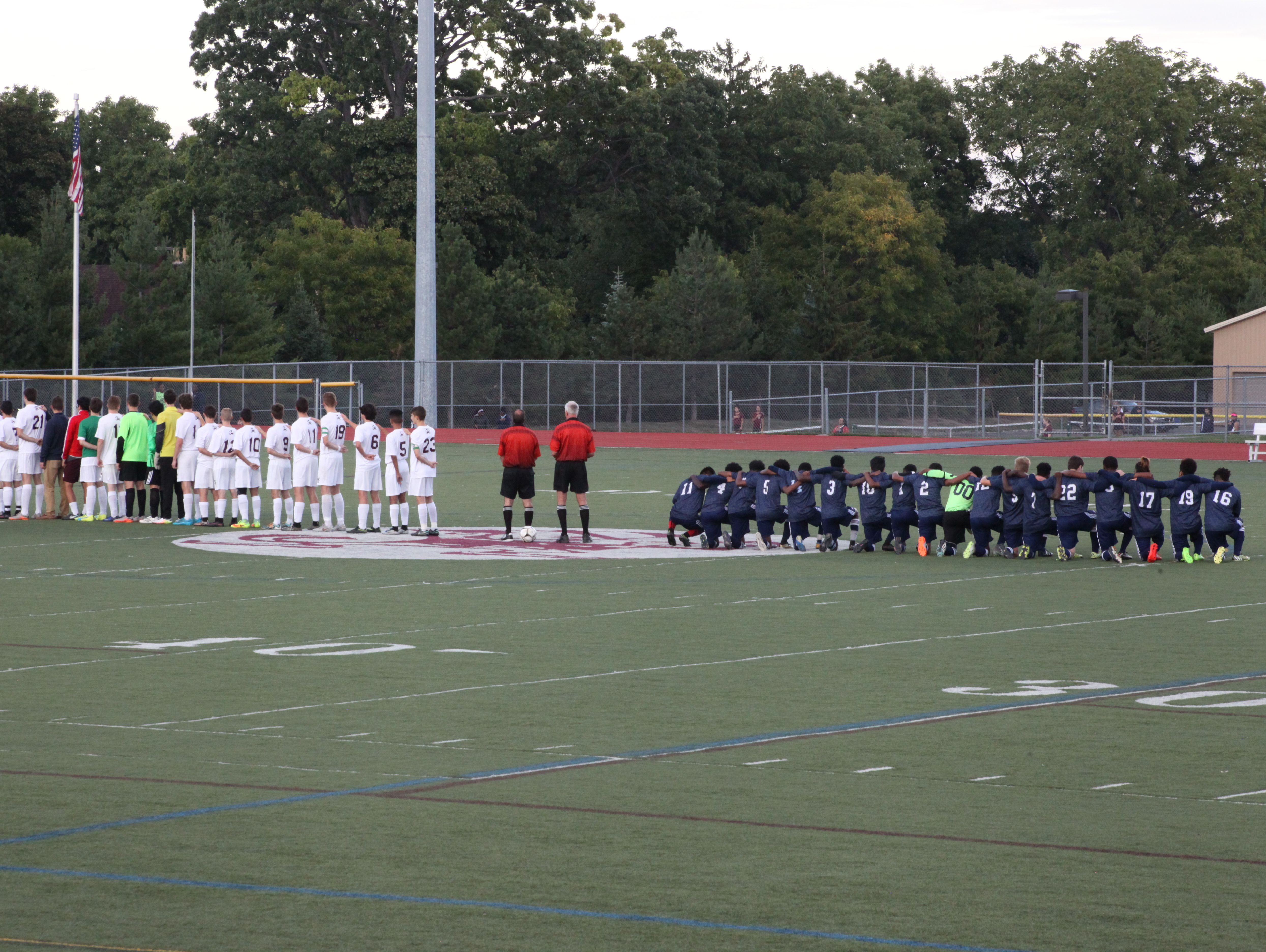 School 58/World of Inquiry boys soccer players kneel during the national anthem prior to their game Tuesday with Aquinas.