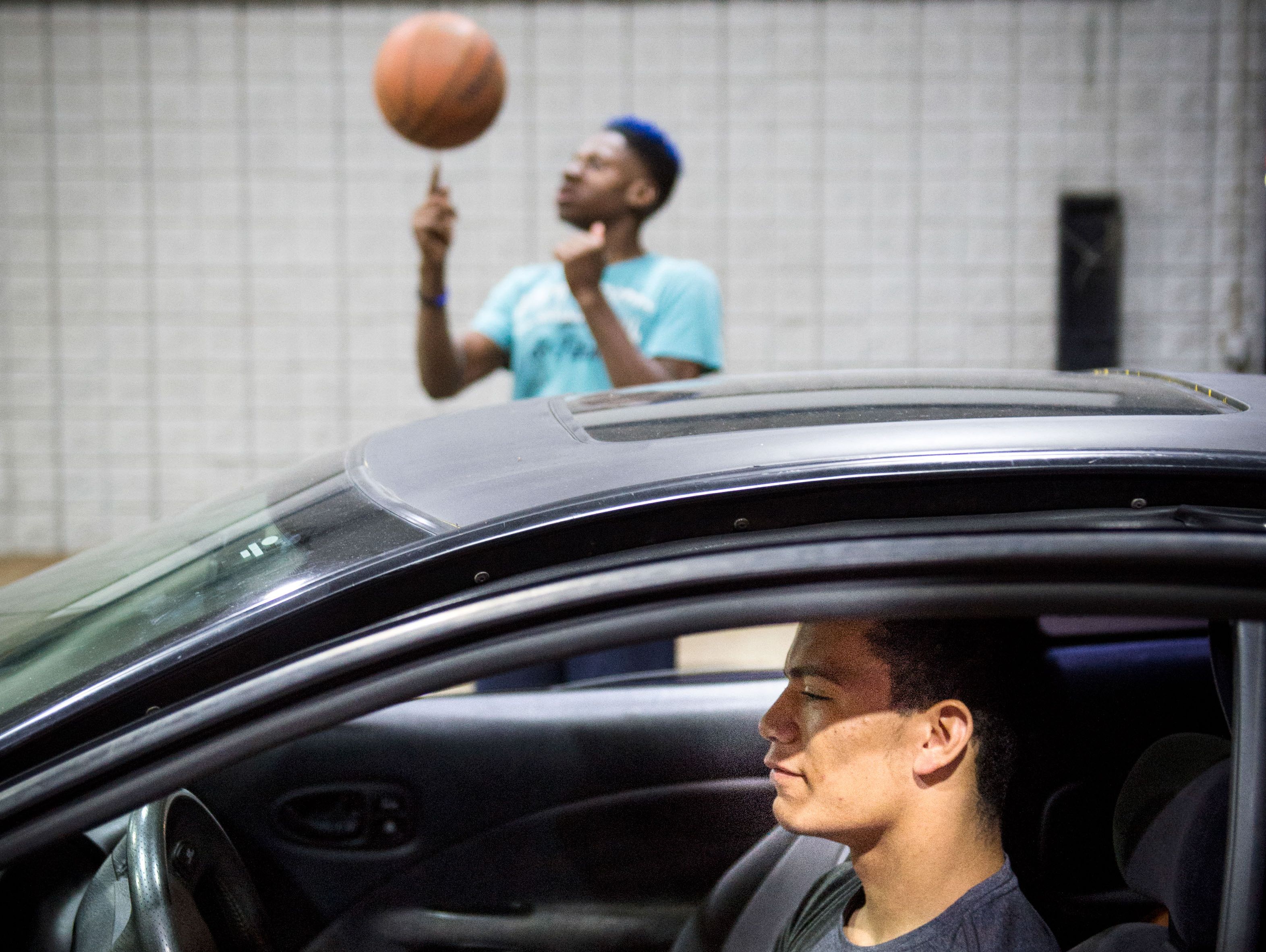 Shawn Murphy attempts to start his car as his friend Kevric Fifer, 17, spins a basketball, while experiencing car trouble on his way home from football practice, Tuesday, Oct. 25, 2016, in Nashville, Tenn.