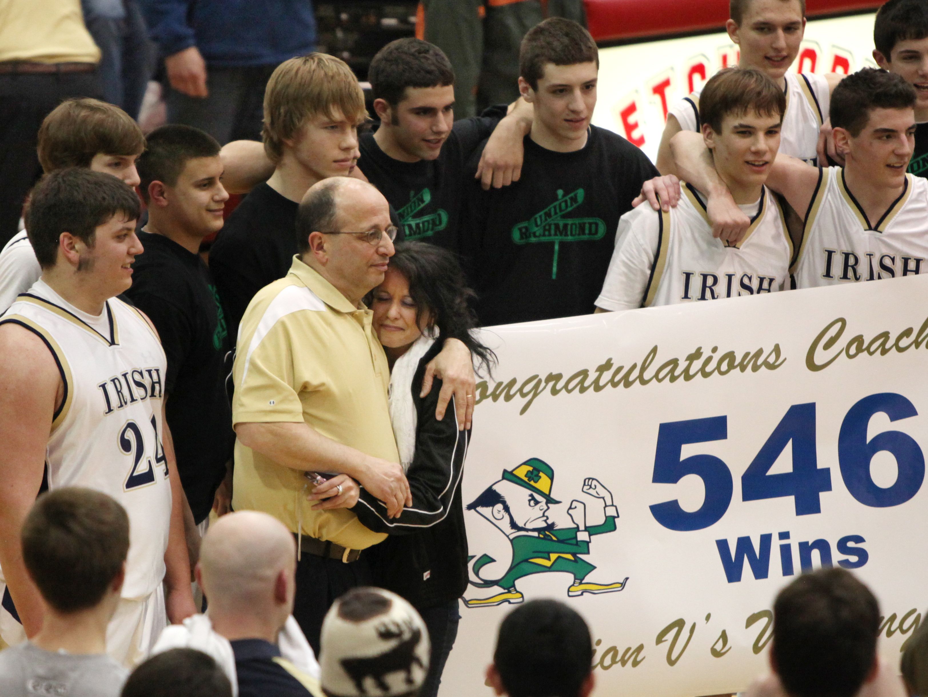 Batavia Notre Dame boys basketball coach Mike Rapone, (left in yellow shirt), is surrounded by family, friends and his players after his team defeated Arkport in their 2010 Section V Class D1 semifinal. He became the winningest coach in Section V boys basketball history on March 3 of that year.