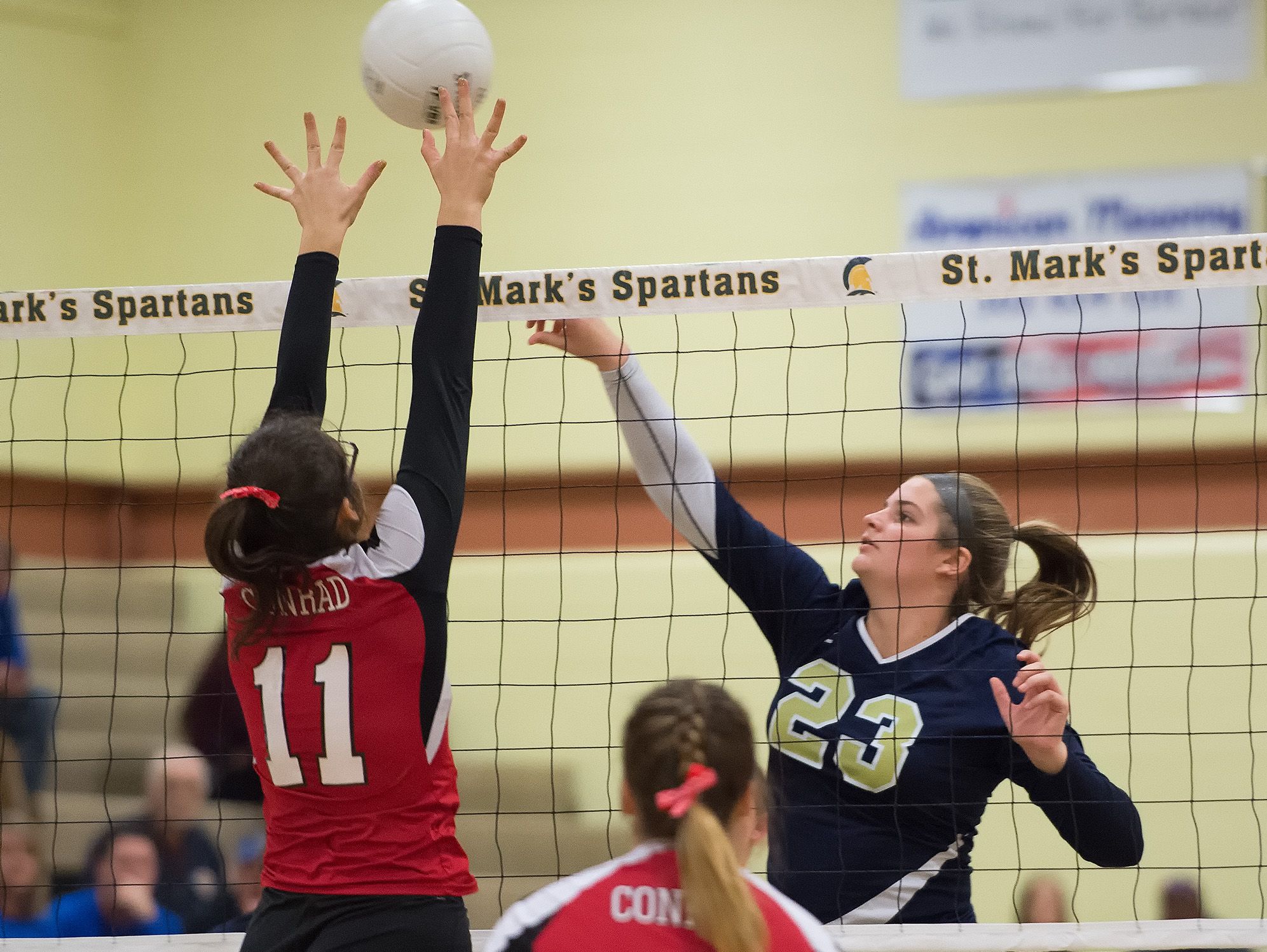 Conrad's Madison Greer (11) tries to block a spike by Delaware Military Academy's Lindsay Wolfe (23) in the second round game of the DIAA State Volleyball Tournament.