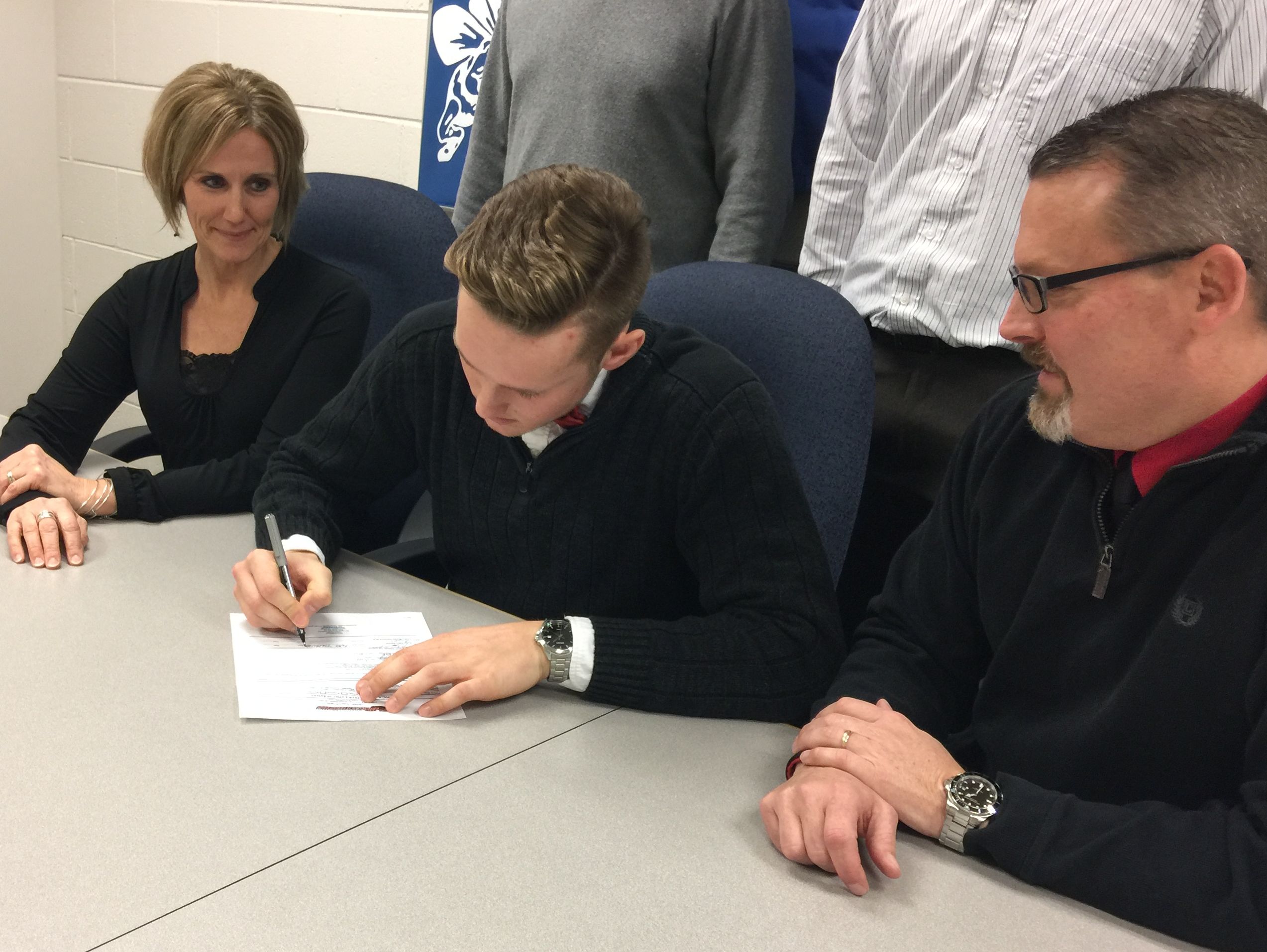 Flanked by his parents, Bath senior Max Tiraboschi, center, signs his national letter of intent to play football at Davenport University on Wednesday, Feb. 1, 2017