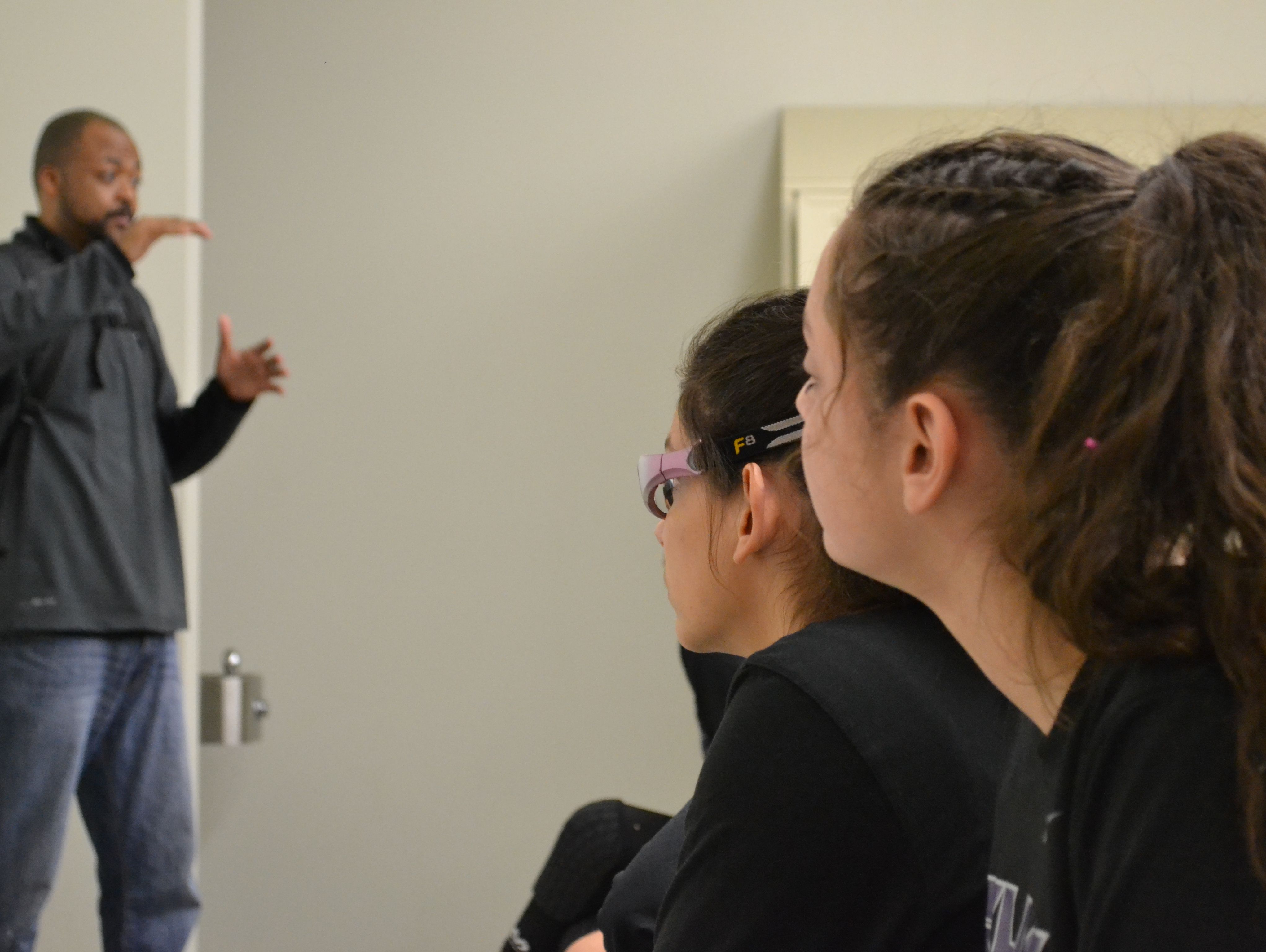 Sisters Mireya (goggles) and Valerie Phlaum, who were born deaf and are on the Shadow Hills girls' basketball team, look on as coach Thaddis Bosley gives instructions.