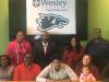 Howard High's Darin Matthews (center) is surrounded by family and friends as he commits to play football and baseball at Wesley College.