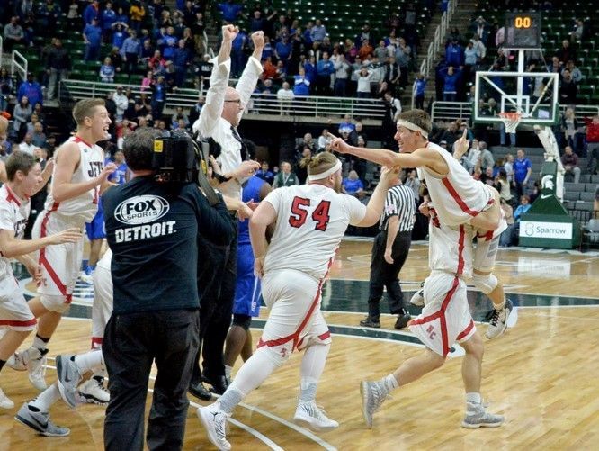Powers North Central senior Seth Polfus is lifted into the air by a teammate after his lay-up beat the buzzer for an 84-83 win in double overtime over Southfield Christian in a Class D semifinal at the Breslin Center on Thursday, March 23.