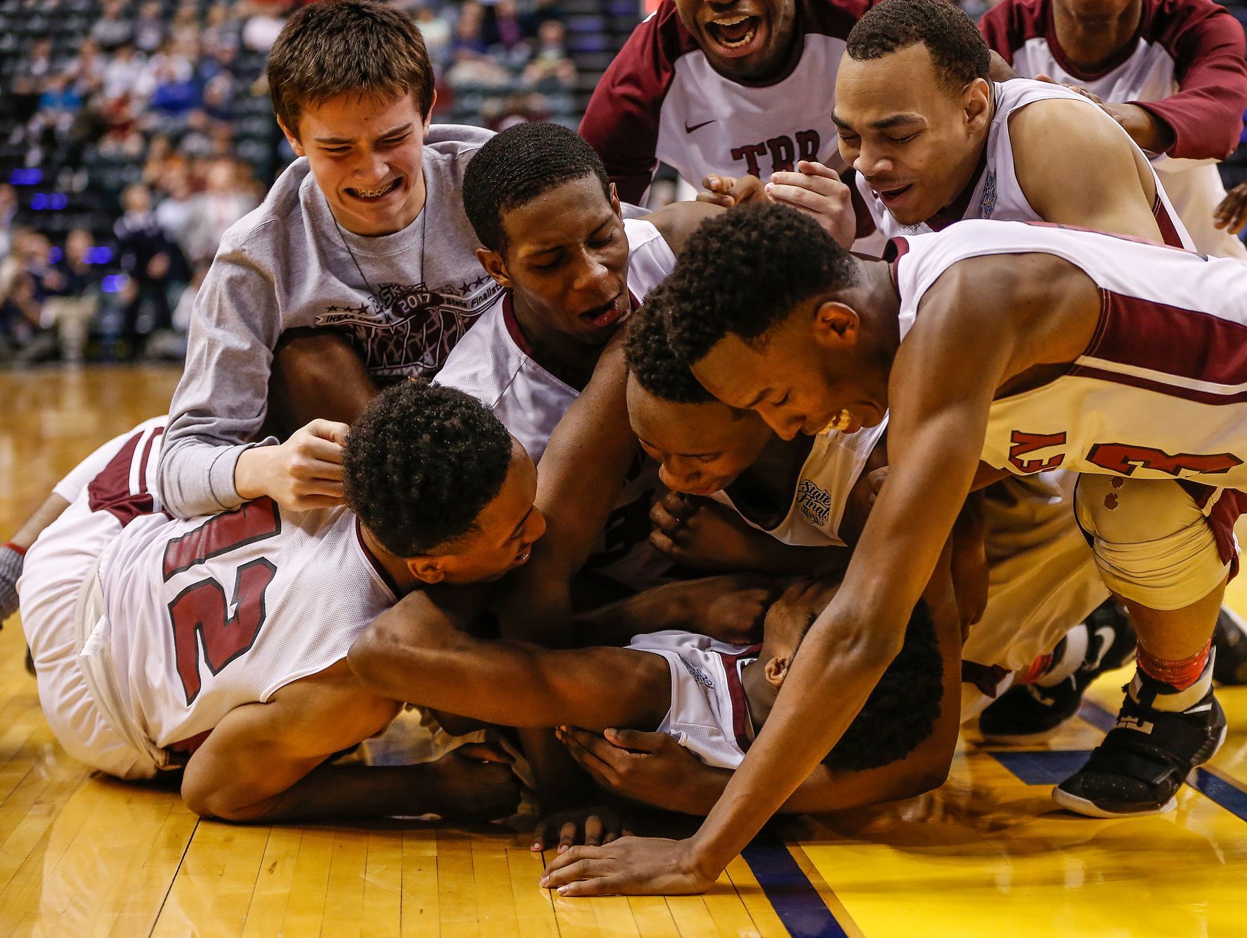 The Tindley Tigers bench clears as they tackle the Tigers’ Hunter White (3) after he connected on a short jumper that put the Tigers up 51-49 over the Lafayette Central Catholic Knights as the time ticked off the clock in the fourth quarter during the IHSAA Class A state championship game at Bankers Life Fieldhouse in Indianapolis on Saturday, March 25, 2017.