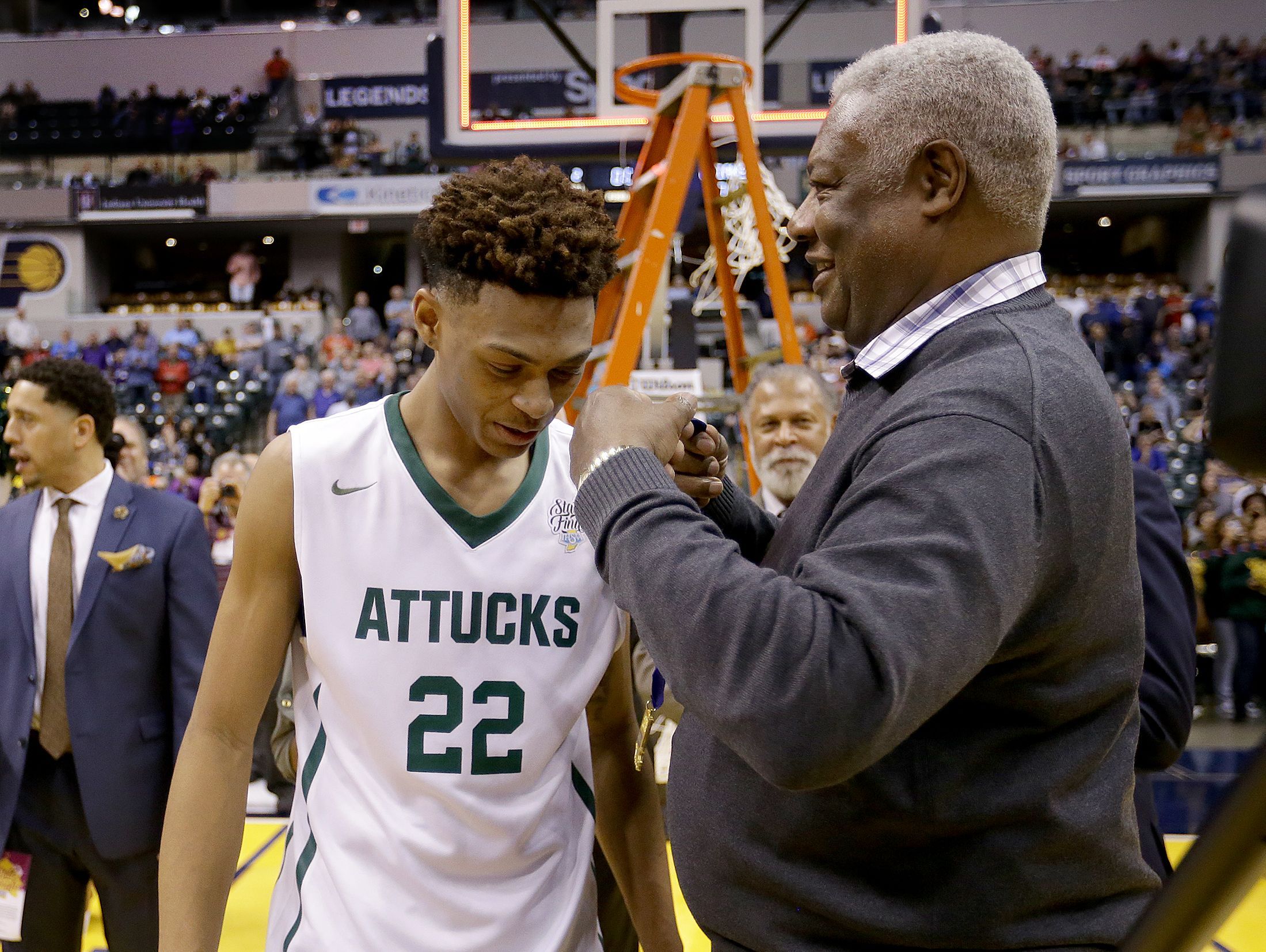 Oscar Robertson looks to put the winning medal around Crispus Attucks' Nike Sibande (22) after winning the IHSAA 3A Boys Basketball State Finals game Saturday, at Bankers Life Fieldhouse.